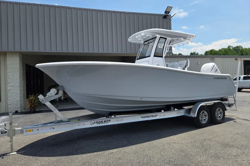 The Image of 2026 Sportsman Open 232 Center Console boat on trailer, parked outside a building. - 0