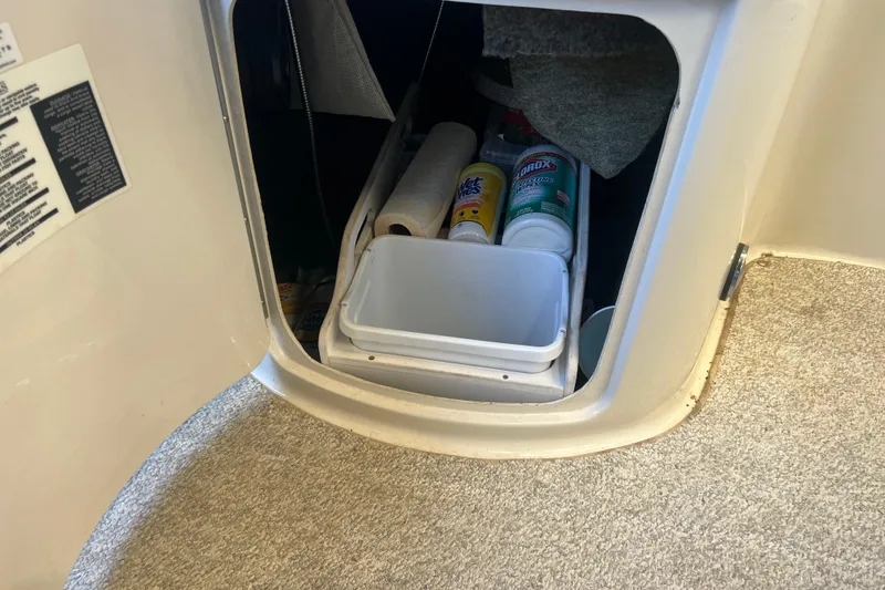 Slide: The Image of Storage compartment in a 2004 Sea Ray 270 Sundeck with cleaning supplies and paper towels. - 23