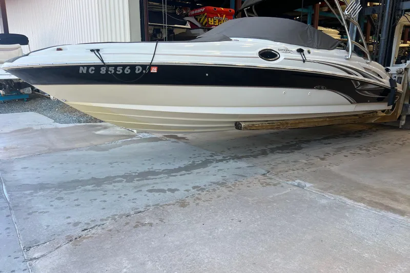 The Image of 2004 Sea Ray 270 Sundeck boat in storage, featuring sleek design and black accents. - 2