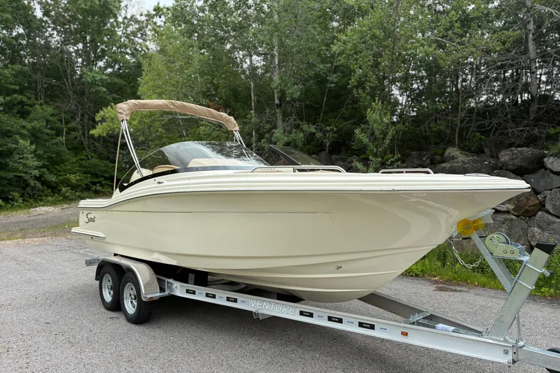 Slide: The Image of 2026 Scout 215 Dorado boat on trailer, surrounded by lush greenery. - 1