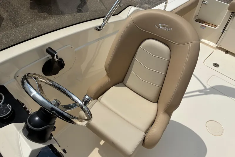 Slide: The Image of 2026 Scout 215 Dorado boat cockpit with beige leather seat and chrome steering wheel. - 10