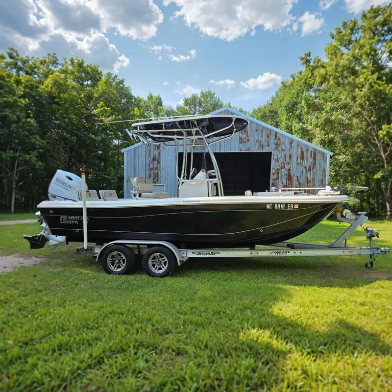 The Image of 2021 Carolina Skiff 21 Ultra Elite boat on trailer, parked near rustic barn. - 0