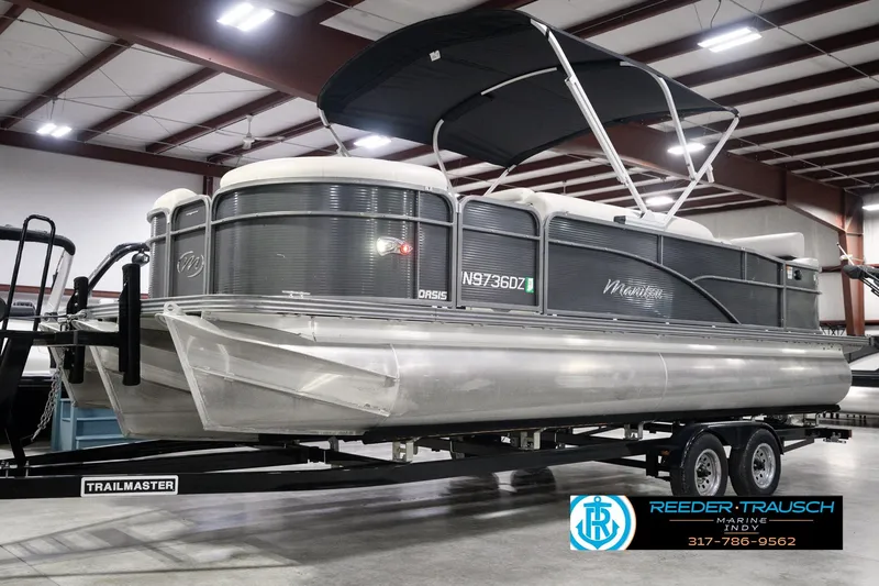Slide: The Image of 2018 Manitou 23 Oasis RF VP pontoon boat on a trailer in a showroom. - 2