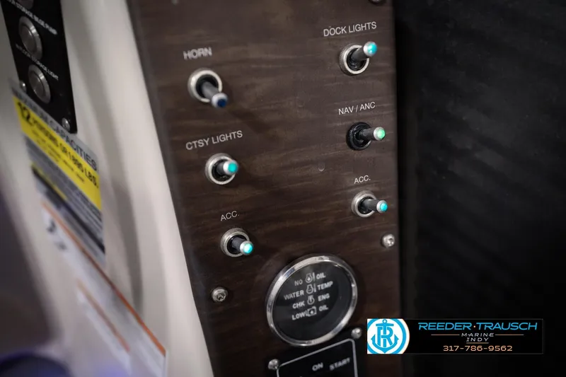Slide: The Image of Control panel of a 2018 Manitou 23 Oasis RF VP boat with labeled switches. - 52