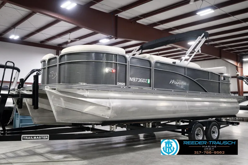 Slide: The Image of 2018 Manitou 23 Oasis RF VP pontoon boat on a trailer in a showroom. - 1