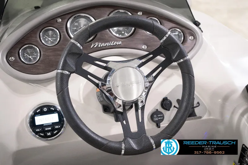 Slide: The Image of Steering wheel and dashboard of 2018 Manitou 23 Oasis RF VP boat, featuring gauges and controls. - 42