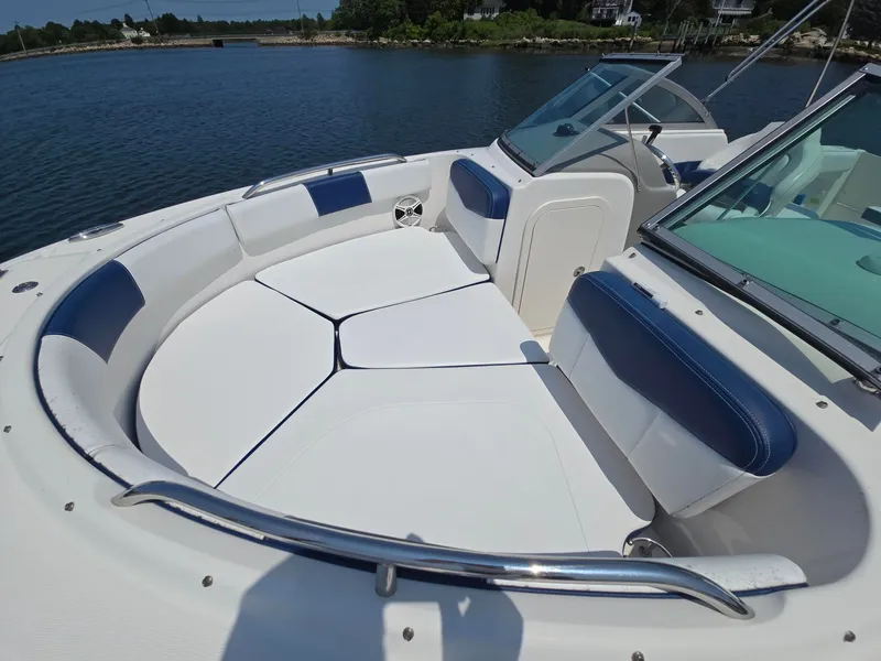 Slide: The Image of The image shows the bow seating area of a 2018 Robalo R227 Dual Console boat with white and blue upholstery. - 35