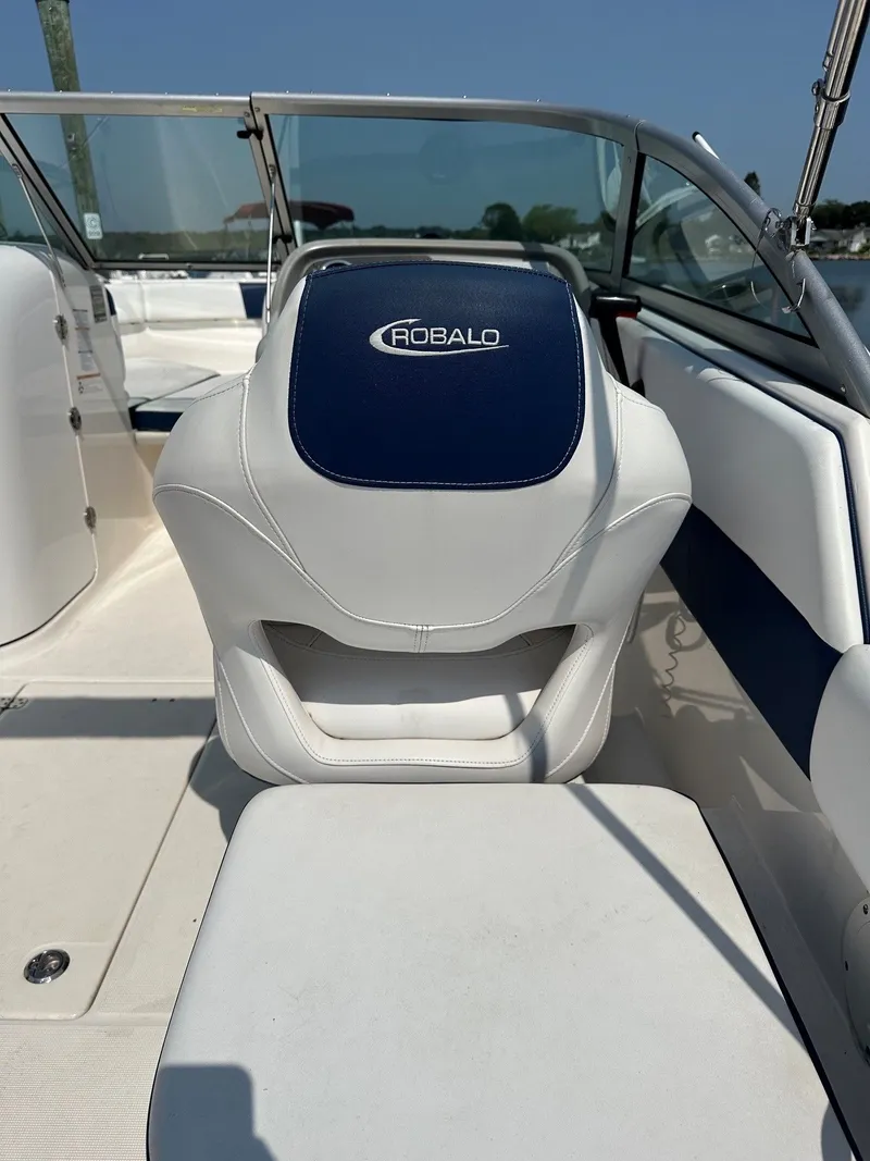 Slide: The Image of The interior of a 2018 Robalo R227 Dual Console boat with white and blue seating. - 19