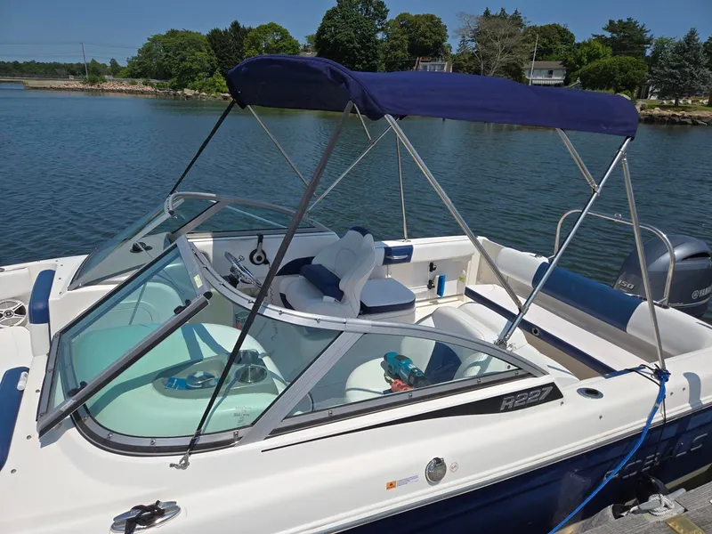 Slide: The Image of A 2018 Robalo R227 Dual Console boat is docked by the water. It features a blue sunshade. - 31