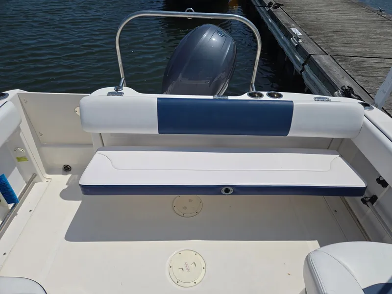 Slide: The Image of The image shows the stern of a 2018 Robalo R227 Dual Console boat with a blue and white bench seat. - 38