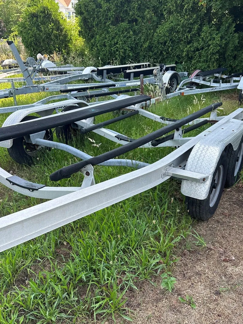 Slide: The Image of A boat trailer sits on grassy ground, surrounded by trees and other trailers. - 25