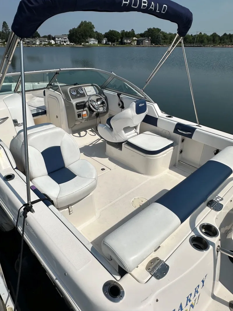Slide: The Image of A 2018 Robalo R227 Dual Console boat on calm water. It features white and blue seating. - 9