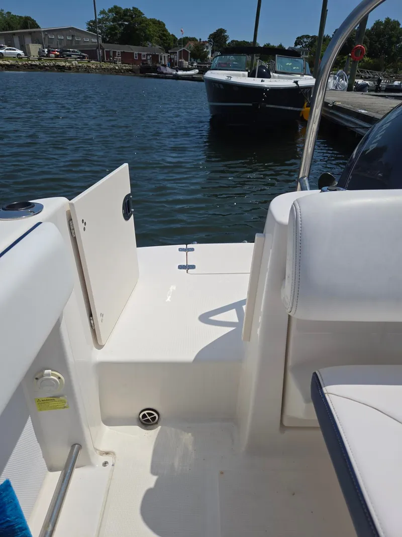 Slide: The Image of The image shows the stern of a 2018 Robalo R227 Dual Console boat docked at a pier. - 40