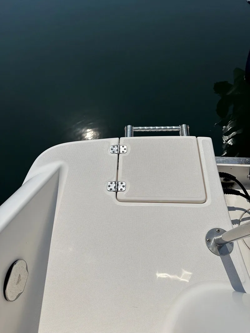 Slide: The Image of The image shows the stern of a 2018 Robalo R227 Dual Console boat with a swim platform. - 18