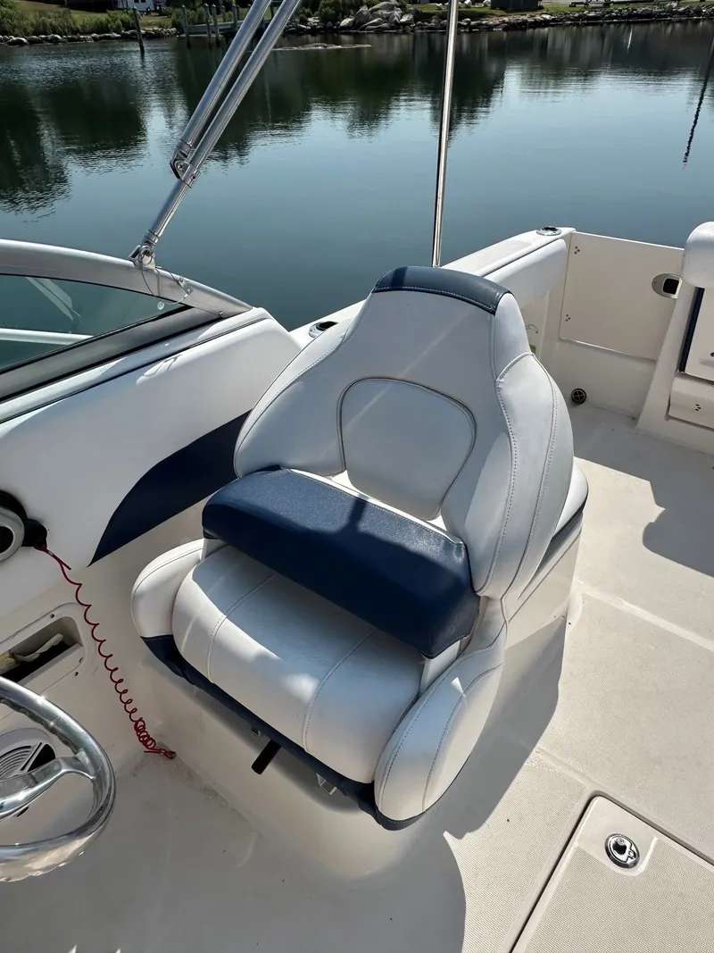 Slide: The Image of A white and blue boat seat on a 2018 Robalo R227 Dual Console, with calm water in the background. - 15