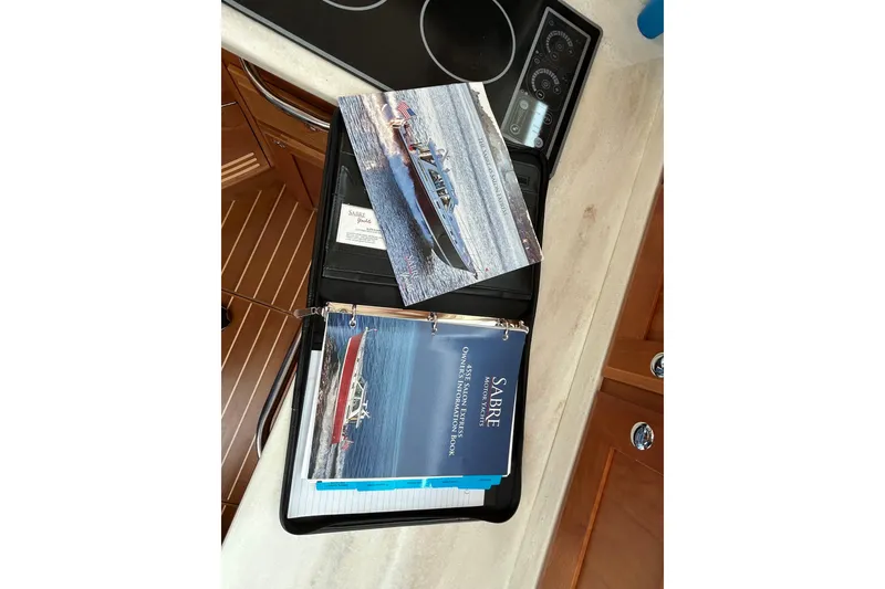 Slide: The Image of Binder with Sabre 45 Salon Express 2022 brochures on a yacht's kitchen counter. - 55