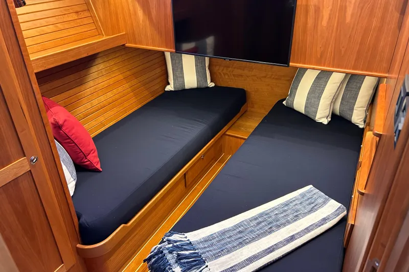 Slide: The Image of 2022 Sabre 45 Salon Express cabin with twin beds, striped pillows, and wooden interior. - 55