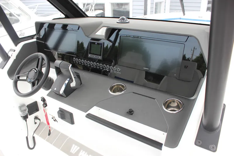 Slide: The Image of 2027 Wellcraft 28 T-Top boat dashboard with steering wheel, controls, and navigation screens. - 31