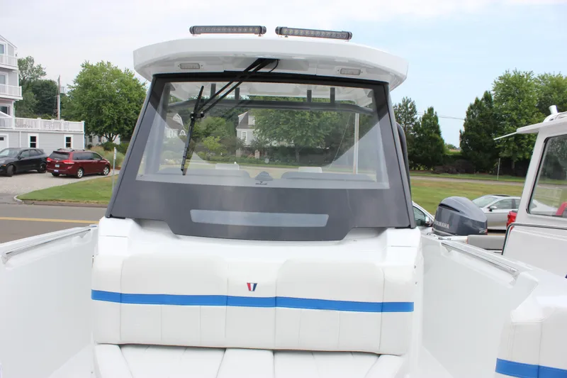 Slide: The Image of 2027 Wellcraft 28 T-Top boat, rear view, parked on a street with houses and trees. - 51