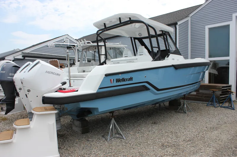 The Image of 2027 Wellcraft 28 T-Top boat with Mercury engine, displayed outdoors on stands. - 0