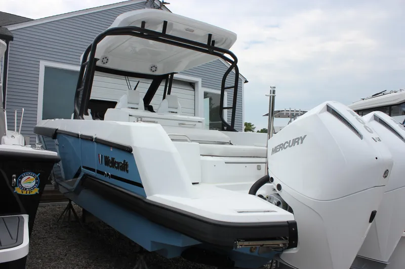 Slide: The Image of 2027 Wellcraft 28 T-Top boat with dual Mercury engines, docked near a building. - 9