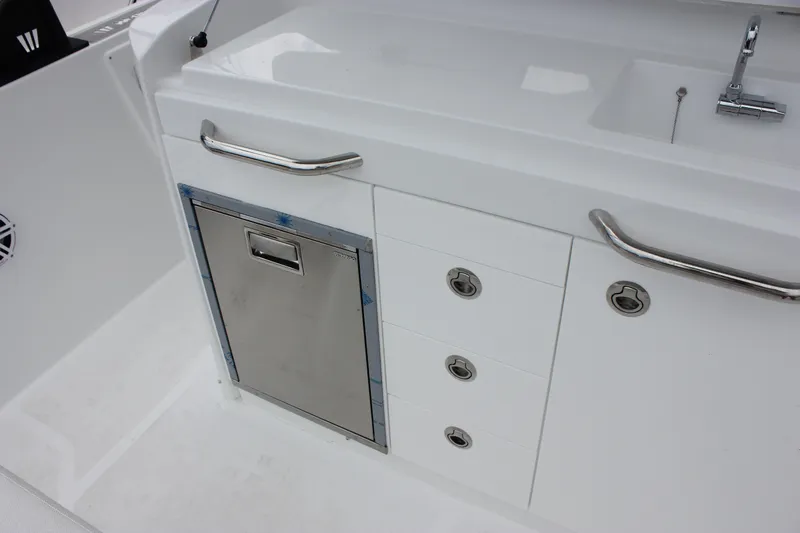 Slide: The Image of 2027 Wellcraft 28 T-Top boat interior with sink, storage drawers, and stainless steel handles. - 22