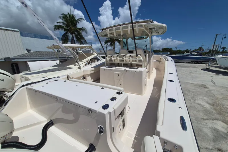 Slide: The Image of 2027 Grady-White Canyon 336 with spacious deck and seating area, docked under a blue sky. - 21