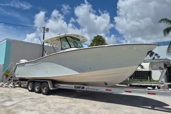 Slide: The Image of A 2027 Grady-White Canyon 336 boat on a trailer under a cloudy sky. - 2