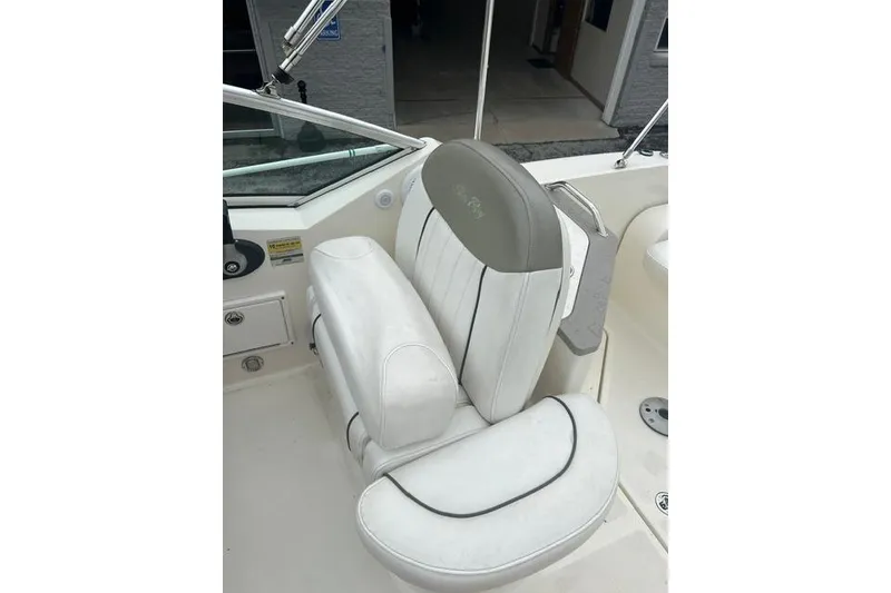 Slide: The Image of Captain's seat on a 2006 Sea Ray 240 Sundancer boat, featuring white upholstery. - 12