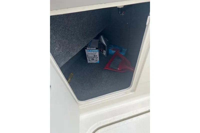 Slide: The Image of Storage compartment of 2006 Sea Ray 240 Sundancer with cleaning supplies and maintenance items. - 13
