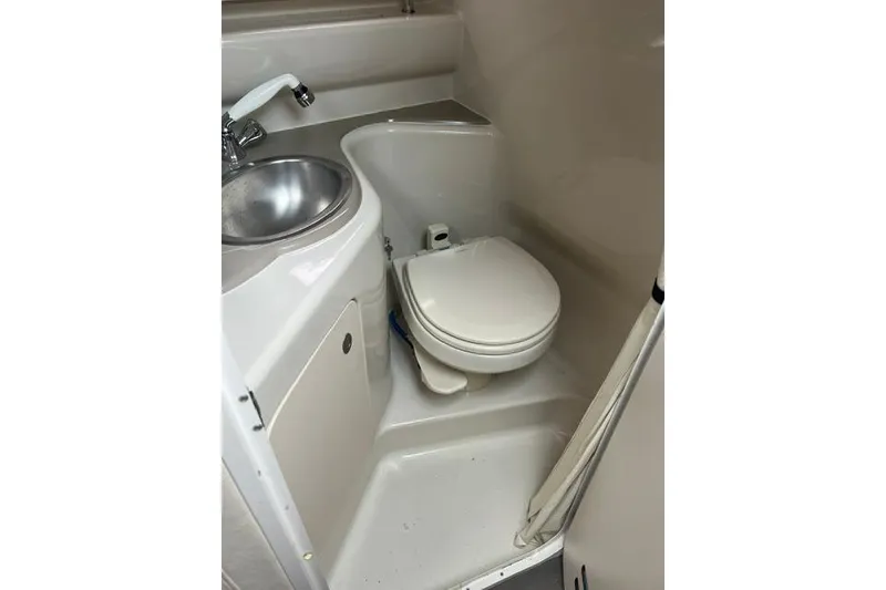 Slide: The Image of Compact bathroom in a 2006 Sea Ray 240 Sundancer boat, featuring a toilet and sink. - 7