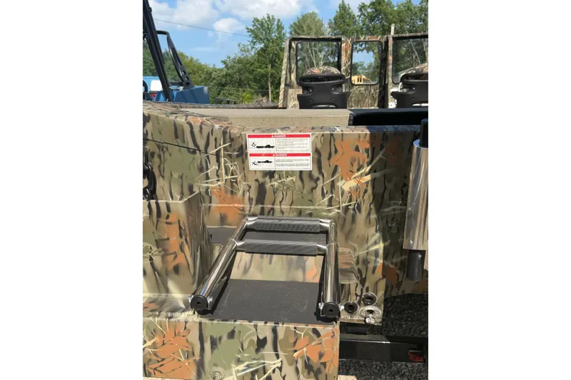 Slide: The Image of 2025 SeaArk 2272 MVT boat with camouflage design and ladder, outdoors. - 11