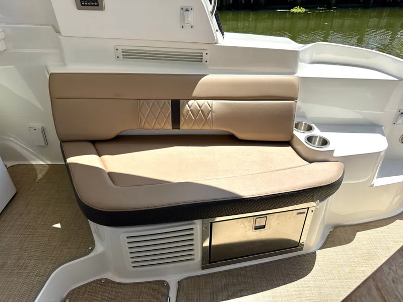 Slide: The Image of Seating area on a 2017 Sea Ray Sundancer 350 Coupe with beige upholstery and cup holders. - 10