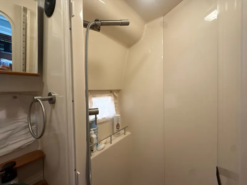Slide: The Image of Interior view of a shower cabin with a handheld showerhead and shelf. - 33