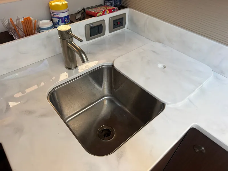 Slide: The Image of A modern kitchenette with a stainless steel sink and faucet, surrounded by white countertops. - 25