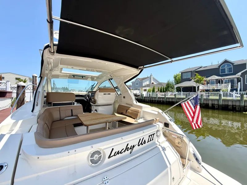 Slide: The Image of The image shows a 2017 Sea Ray Sundancer 350 Coupe docked, featuring a sunshade over the cockpit and an American flag at the stern. - 5