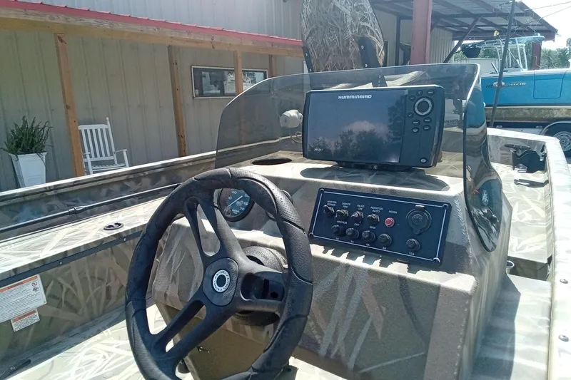 Slide: The Image of 2025 Lund 1760 Predator SC boat dashboard with steering wheel and Humminbird fish finder. - 18