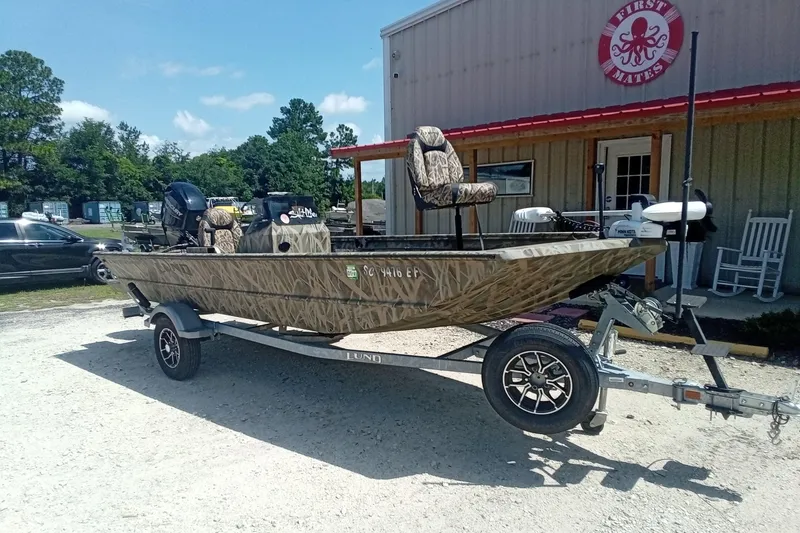 Slide: The Image of 2025 Lund 1760 Predator SC boat on trailer, parked outside a building. - 7