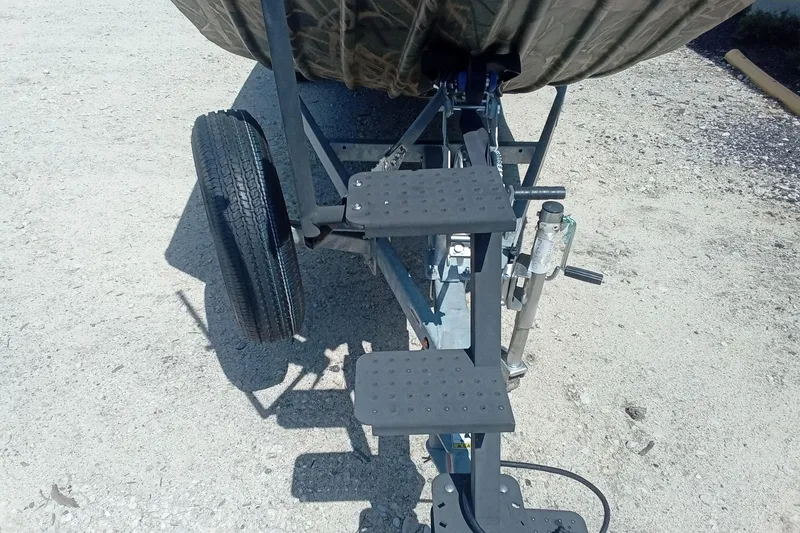 Slide: The Image of Trailer steps and wheel of 2025 Lund 1760 Predator SC boat on gravel surface. - 9