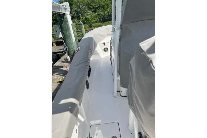 Slide: The Image of 2023 Seafox 268 boat deck with protective covers, docked near lush greenery. - 13