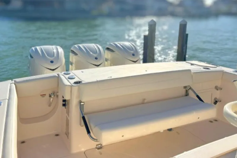 Slide: The Image of 2025 Grady-White Canyon 336 boat with triple outboard engines, docked on calm water. - 19