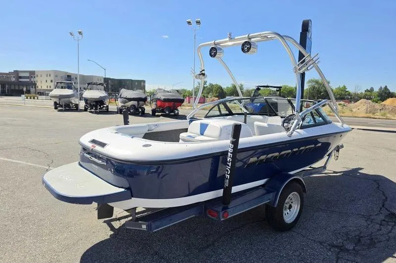 Slide: The Image of 1998 Moomba Outback boat on trailer in parking lot, featuring blue and white design. - 15