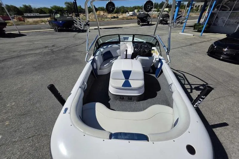 Slide: The Image of 1998 Moomba Outback boat interior with white and blue seating, parked outdoors. - 11