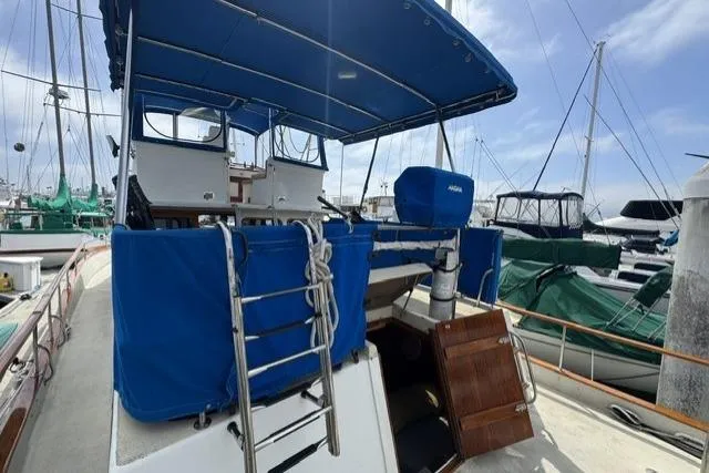 Slide: The Image of 1977 Californian 38 Motor Yacht with blue canopy docked at marina. - 41