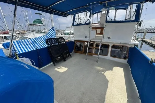Slide: The Image of 1977 Californian 38 Motor Yacht with spacious deck, blue canopy, and marina view. - 43