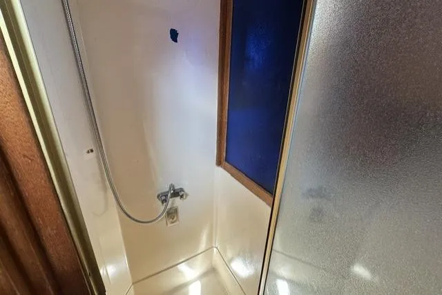 Slide: The Image of Shower area in a 1977 Californian 38 Motor Yacht, featuring a handheld showerhead and frosted glass door. - 18