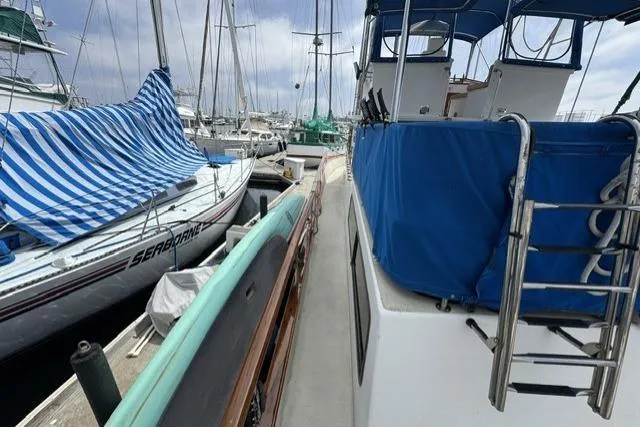 Slide: The Image of 1977 Californian 38 Motor Yacht docked, featuring blue covers and adjacent sailboats. - 42