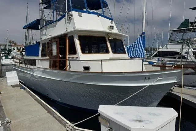 Slide: The Image of 1977 Californian 38 Motor Yacht docked at marina with blue canopy and wooden accents. - 1