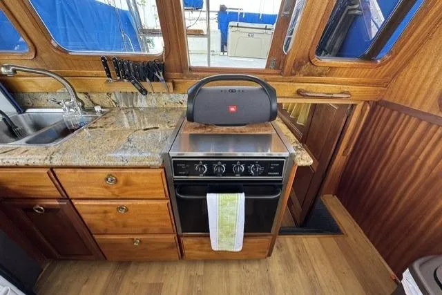 Slide: The Image of 1977 Californian 38 Motor Yacht kitchen with stove, granite countertop, and wooden cabinetry. - 13