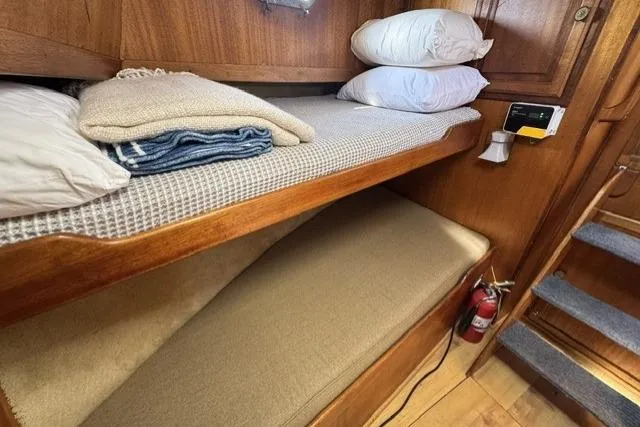 Slide: The Image of 1977 Californian 38 Motor Yacht cabin with bunk beds, pillows, blankets, and a fire extinguisher. - 19